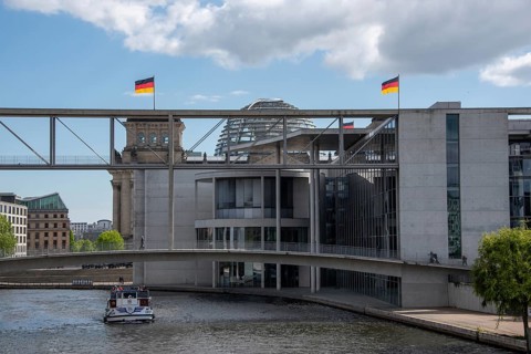 Modern building in Berlin's government district with Reichstag building, German flags and the