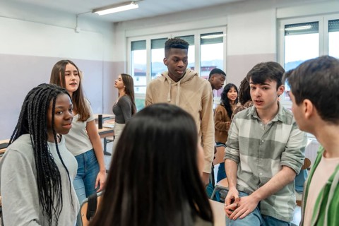 Multi ethnic group of high school students chatting and interacting during break time inside a