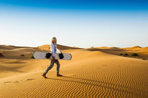 Young woman with snowboard in the sand dunes, near Merzouga, Meknès-Tafilalet region, Erg Chebbi,