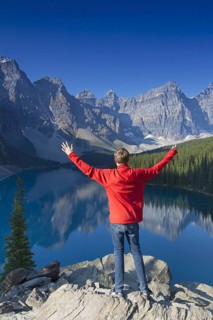 Tourist with open arms on look-out point looking over Moraine Lake in the Valley of the Ten Peaks,