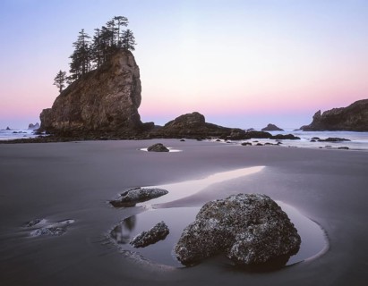 Soft pastel hues color the sky as dawn breaks over Second Beach. Sea stacks, tide pools, and wet