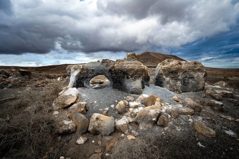 Eroded rock formations in volcanic landscape with dramatic cloudy skies, Ciudad Estratificada or