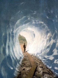 A man standing at the entrance to an ice cave at the Grindelwald Grotto, in the Bernese Alps,