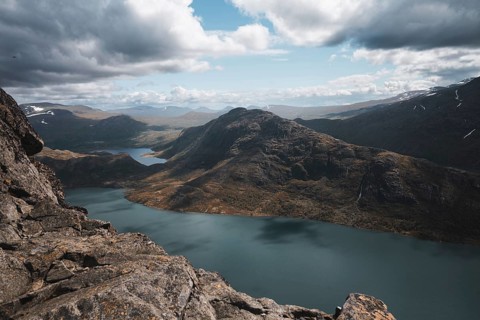 An expansive view of Norway's mountainous terrain, featuring a pristine lake surrounded by rugged