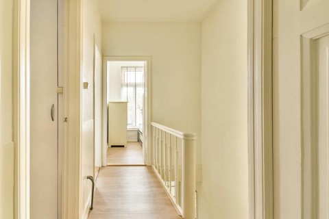 A well-lit hallway features white walls and wooden flooring, creating an inviting and spacious