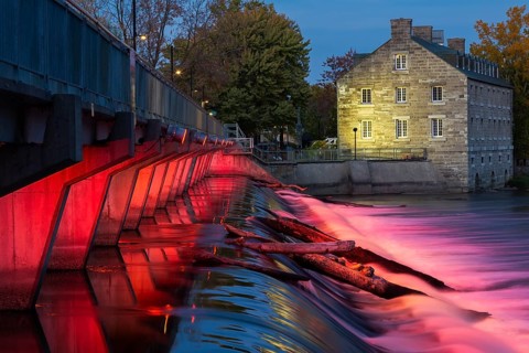 Illuminated Moulin Neuf water flow control dam and walkway over Des Mille-Iles river plus New Mill