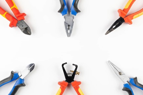 Several colorful pliers arranged in a circle on a white background