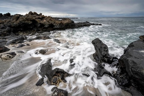 Waves blaze on the beach, rocky coast with volcanic stones, long exposure, Playa de la Pequeña,
