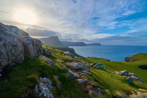 The sun breaks through the clouds over green cliffs and blue sea, Waterstein Head, Waterstein, Isle