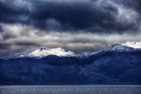 Snowy mountain peaks under dark, dramatic ocean clouds, Chile, South America