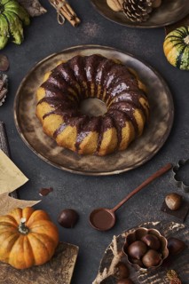 From above tasty appetizing pumpkin cake with chocolate cream on table decorated with autumn