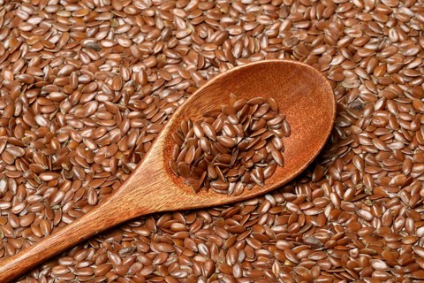 Linseed with wooden spoon, seeds of the common flax (Linum usitatissimum)