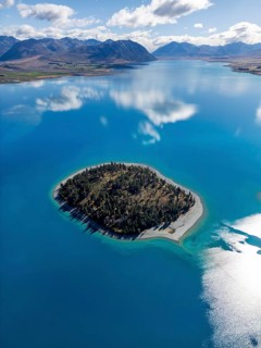 Aerial view of Lake Tekapo in Canterbury, New Zealand, showcasing a small forested motuariki island