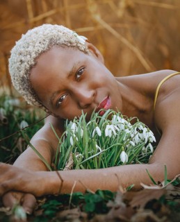 A serene moment captured as a woman rests peacefully among snowdrop flowers, embodying a deep