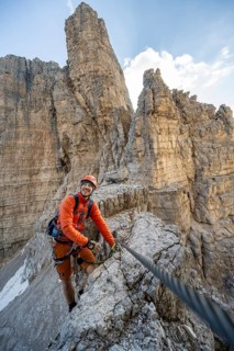 Mountaineer climbs an exposed rock in the secured Via Ferrata Bocciere Centrale via ferrata,