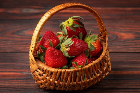 Fresh strawberries in a basket on dark wood