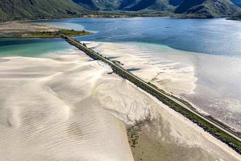 Aerial view of a bridge over turquoise sea at a sandy beach, fjord Grunnforfjorden, Lofoten