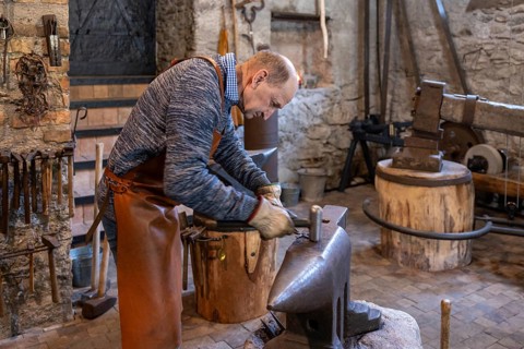 An elderly blacksmith passionately maintains the centuries-old craft of blacksmithing in his rustic