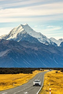 A picturesque view of Mount Cook, New Zealand, during autumn. The winding road and golden fields
