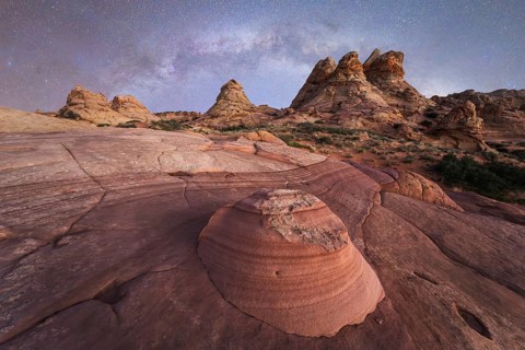 Breathtaking desert landscape showcasing layered rock formations beneath a star filled night sky,