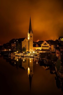 View of Hallstatt with the church and Lake Hallstatt at night. Clouds move through Hallstatt.