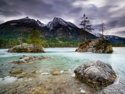 Rocks in frozen Hintersee, high cold and blurred clouds above, long exposure, Berchtesgaden
