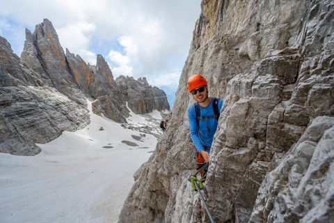 Mountaineer climbs on a steep rock face in the Via Ferrata dell'Ideale via ferrata, spectacular
