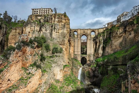 Wide angle view from the bottom of the gorge featuring the massive arches of Puente Nuevo bridge