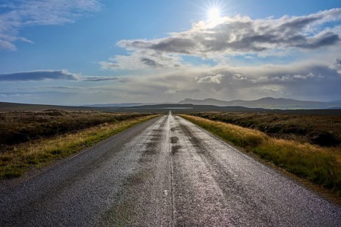 An illuminated road runs through a vast landscape under cloudy skies and strong sunlight, Tongue,