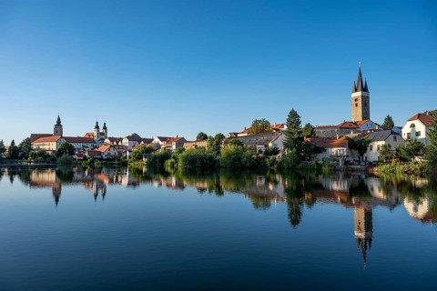 A wide panoramic view of the historic town of Telc with its colorful buildings and church towers