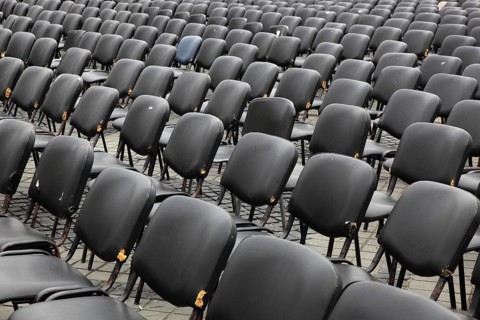 Chairs covered with gray plastic stand in rows in a function room, empty, vacant, seating