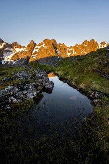 Rocky mountain peaks with reflection, small pond in moor landscape at Trollfjord Hytta, mountain