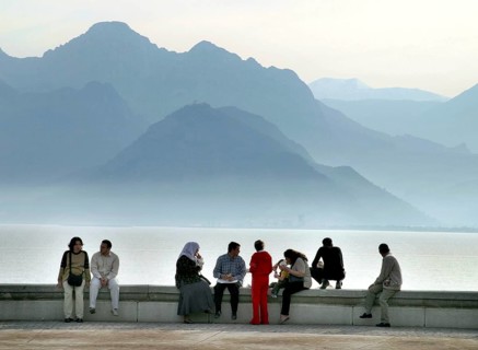 Antalya, TUR, 10.04.2004 - Turks sit on a wall on the waterfront in Antalya, Turkey. In the