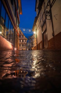 Wet cobblestone alley in historic old town illuminated with Christmas lights, romantic and dreamy,