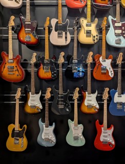 A colorful assortment of electric guitars is displayed on a wall, showcasing a variety of styles