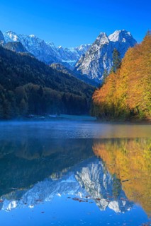 Mountains reflected in lake, fog, morning light, autumn colours, Riessersee, Waxensteine behind,