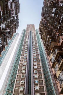 Low angle of towering residential buildings soar, showcasing Hong Kong's dense urban architecture.