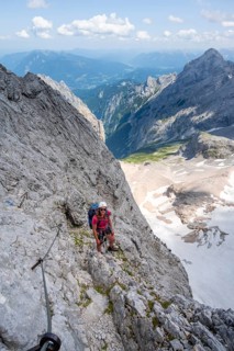 Mountaineer with helmet climbing in a secured via ferrata, Zugspitz via ferrata, ascent to the