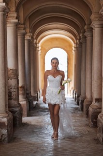 A bride walks elegantly through the ancient arches of a historic villa in Treia, Macerata. Her