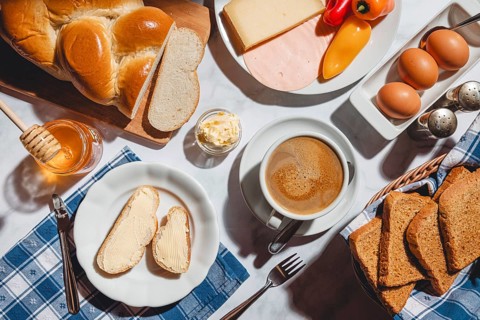 Breakfast with toast, sliced stollen, honey, cheese, ham, coffee, butter, bell pepper and eggs