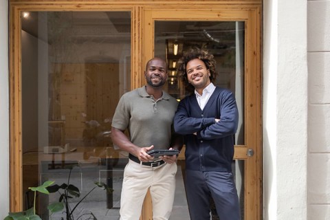 Two professionals stand confidently outside a stylish coworking space in Barcelona, illustrating