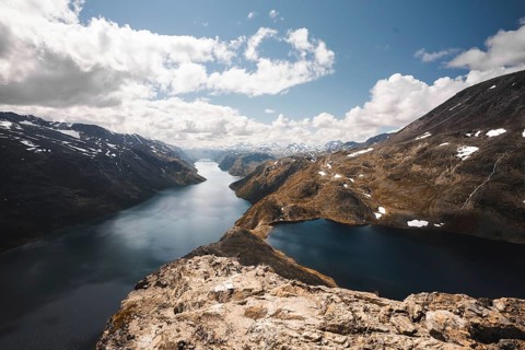 A panoramic view of glistening mountain lakes and towering peaks in Norway The rocky foreground