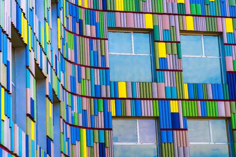A close-up view of a modern building's facade featuring a vibrant, multicolor pattern with distinct