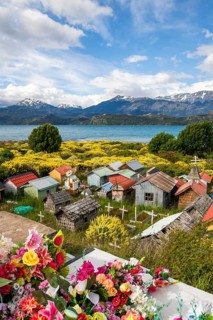 Colourful plastic flowers and graves with miniature houses made of corrugated iron and wooden
