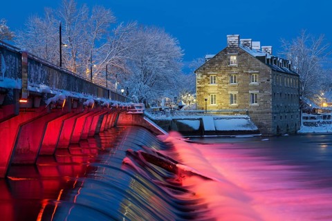 Illuminated Moulin Neuf water flow control dam and walkway over Des Mille-Iles river plus New Mill