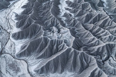Stark aerial perspective of Caineville Mesa near Hanksville, Utah, coated in snow, highlighting the