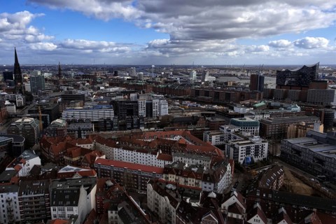 Panoramic view of Hambüg with many old and modern buildings, harbor in the background, cloudy sky,