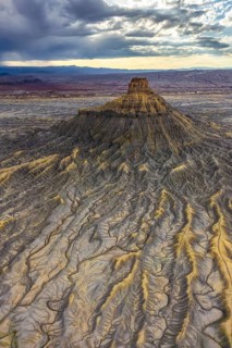 A striking aerial photograph captures the ethereal landscape of Factory Butte during sunset in