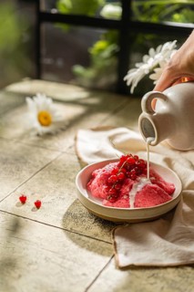 Cropped unrecognizable person hand's pouring cream over homemade berry mousse garnished with fresh