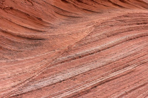 Red sandstone formations create a visually striking abstract texture with layered patterns. The